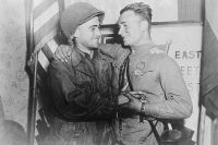 2-й лейтенант У. Робертсон и лейтенант А. С. Сильвашко на фоне надписи «Восток встречается с Западом», символизирующей историческую встречу союзников на Эльбе.