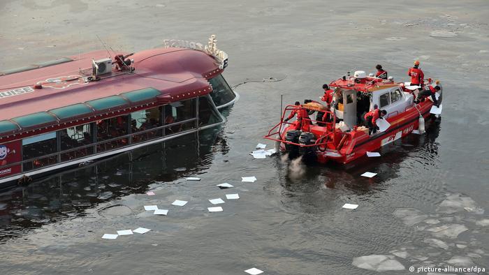 Firefighting officials throw oil absorbents into the Han River in Seoul, South Korea, (photo: picture-alliance/dpa)